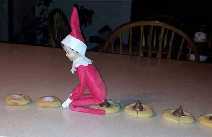 A little elf sits on cookies and drops  chocolate covered poopiees.