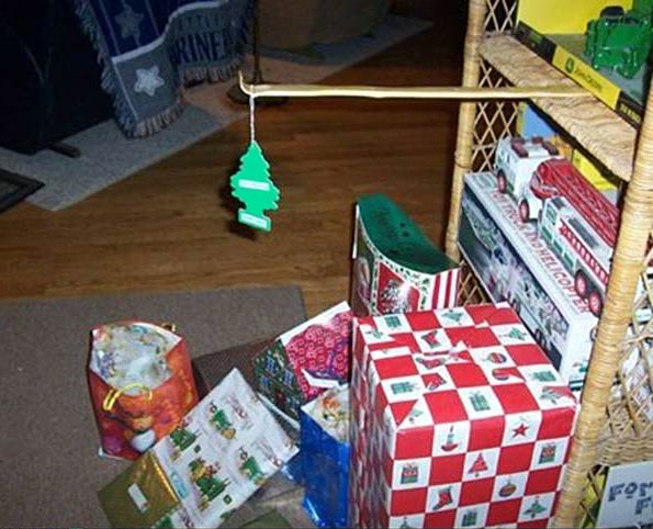 Photo of a few wrapped presents and a back scratcher handing out over the presents holding a pine scented car deoderizer.